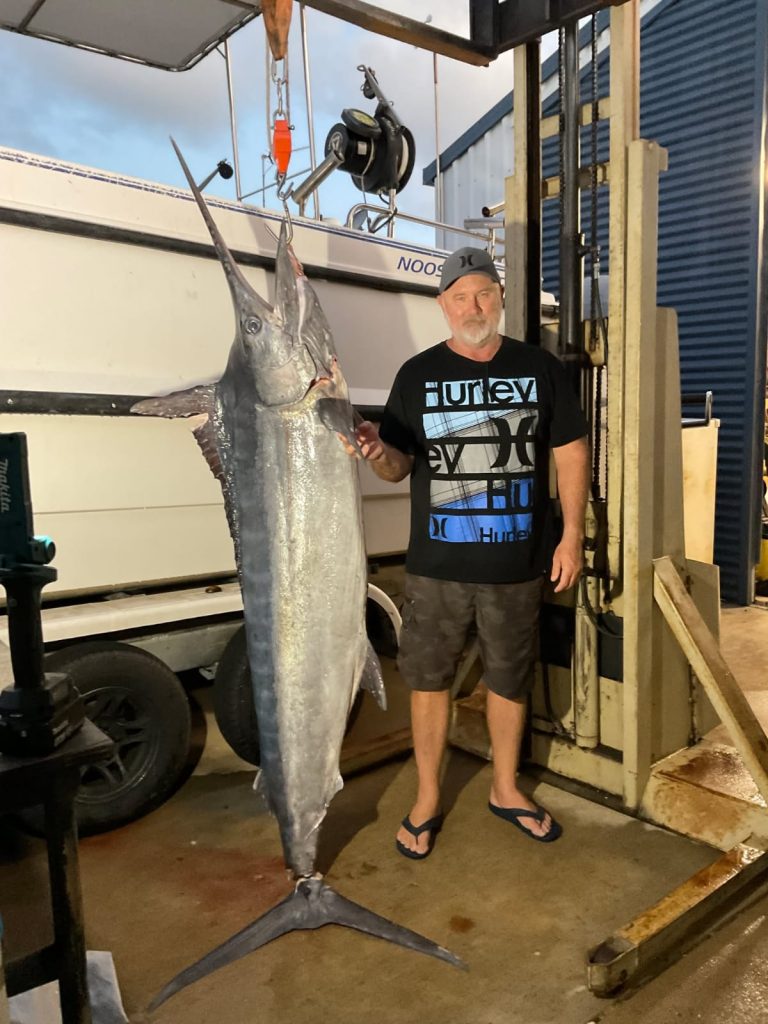 Scott holding an incredible black marlin and with OILWIND jigging machine in background